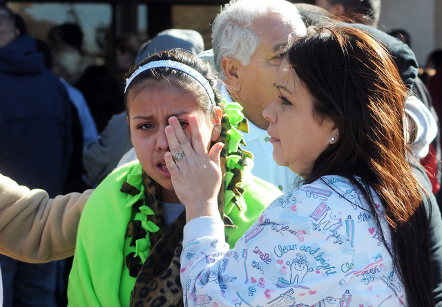 A woman wipes a girl's eyes at a staging ground area set up at the Roswell Mall, where families were united after a shooting at Berrendo Middle School, Tuesday, Jan. 14, 2014, in Roswell, N.M. A s ...