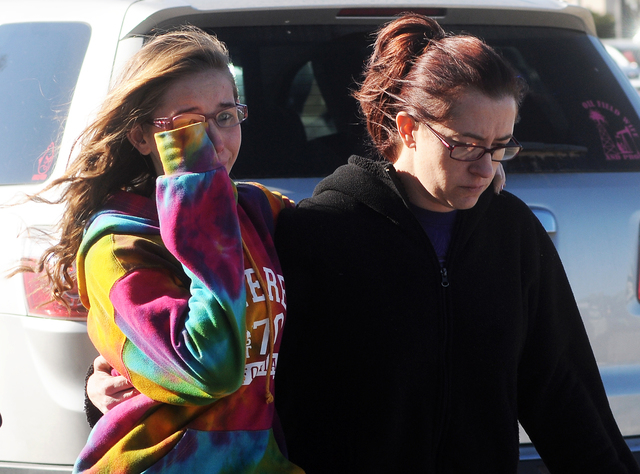 A student, left, walks with a woman at a staging ground area set up at the Roswell Mall, where families were united after a shooting at Berrendo Middle School, Tuesday, Jan. 14, 2014, in Roswell,  ...