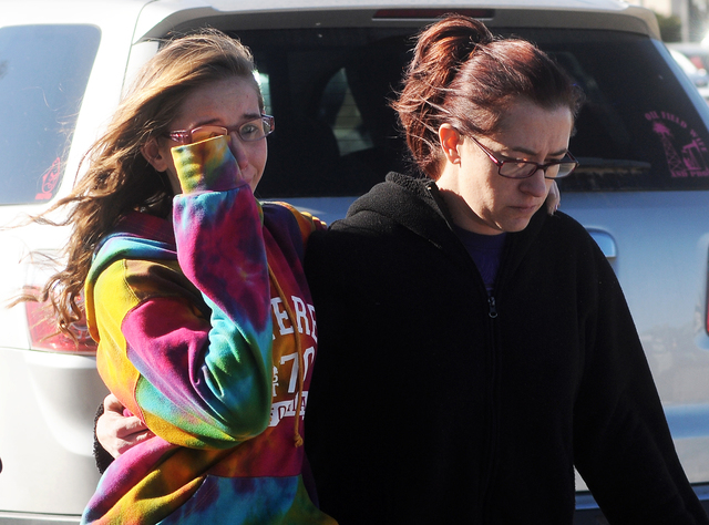 A student, left, walks with a woman at a staging ground area set up at the Roswell Mall, where families were united after a shooting at Berrendo Middle School, Tuesday, Jan. 14, 2014, in Roswell, ...