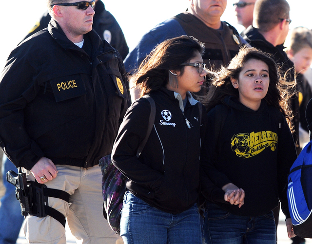 Students surrounded by officials are escorted from Berrendo Middle School after a shooting, Tuesday, Jan. 14, 2014, in Roswell, N.M. Roswell police said the suspected shooter was arrested at the s ...