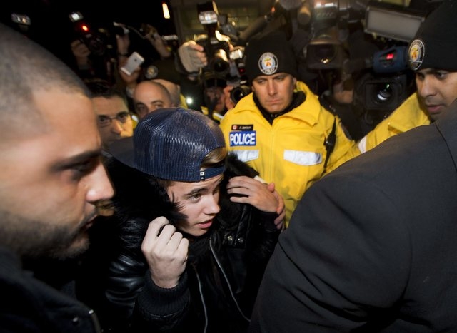 Canadian musician Justin Bieber is swarmed by media and police officers as he turns himself into city police for an expected assault charge, in Toronto, on Wednesday, Jan. 29, 2014. A police offic ...