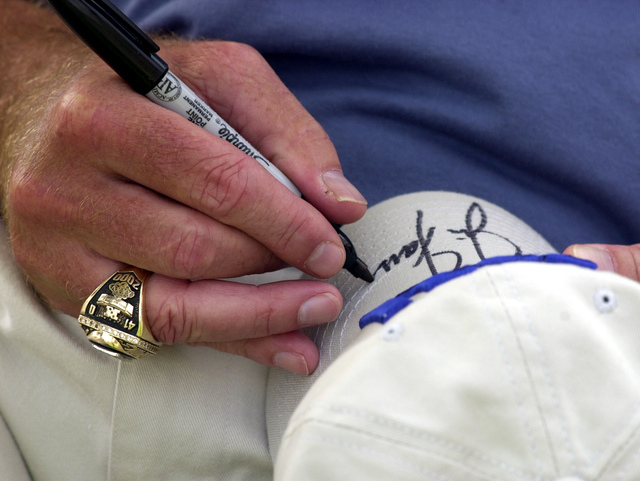 New York Giants head coach Jim Fassel wears his 2000 Super Bowl ring as he signs an autograph on a Giants cap  on Thursday, July 24, 2003, during the Giants media day at the University at Albany i ...