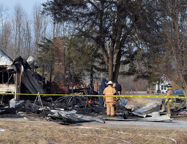 Yellow safety tape marks off the area as Kentucky State Fire investigators examine the scene of early morning house fire near Greenville, Ky., on Thursday. Nine people were killed in the fire in r ...