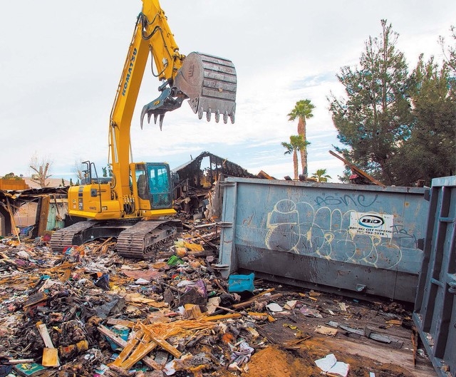 An excavator demolishes the house and contents at 1313 Esther Drive, Thursday Jan. 23, 2014. A Metro Police officer killed his wife and child before taking his own life at the location last year.  ...