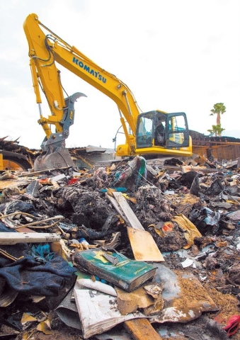 A Las Vegas Metropolitan Police 25th Anniversary book is seen in the foreground as an excavator demolishes the house and contents at 1313 Esther Drive, Thursday Jan. 23, 2014. A Metro Police offic ...