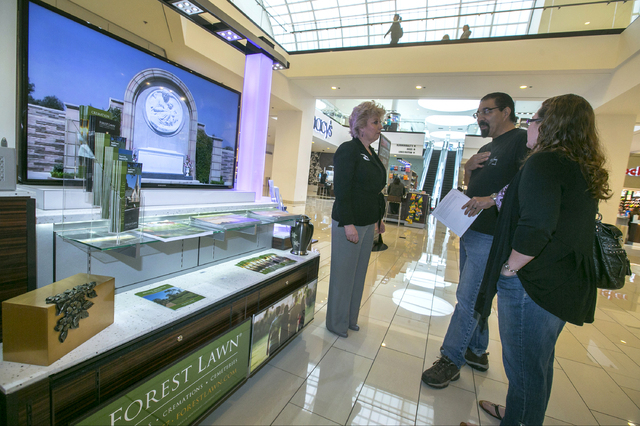 Forest Lawn regional sales manager Hilda Carabes, left, shows Mark Sanchez and his wife, Lea'Anne, at the Forest Lawn stand at the Glendale Galleria mall in Glendale, Calif. Forest Lawn, famous as ...