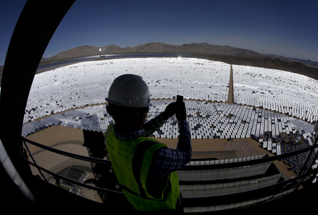 Jeff Holland takes a picture of some of the 300,000 computer-controlled mirrors that reflect sunlight to boilers that sit on 459-foot towers Tuesday, Feb. 11, 2014 in Primm, Nev. The Ivanpah Solar ...