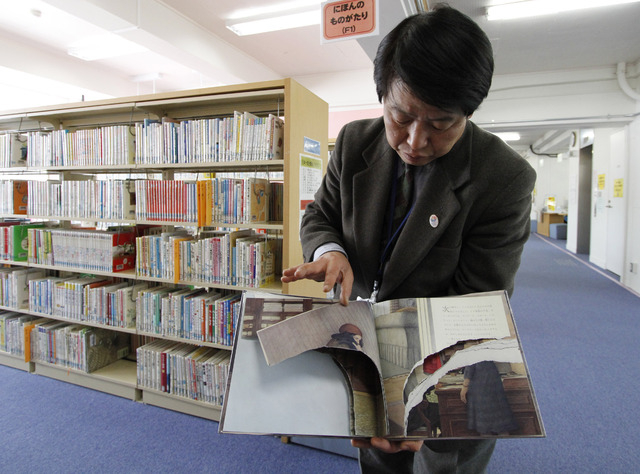 A ripped copy of Anne Frank's "Diary of a Young Girl" picture book is shown by Shinjuku City Library Director Kotaro Fujimaki at the library in Tokyo Friday, Feb. 21, 2014. Tokyo Librari ...