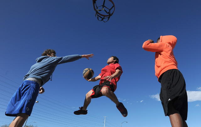 Reid T. shoots for the basket between Ryan Frazer, left and Juvon Adams during pick up basketball game at Desert Breeze Park on Sunday, Jan. 12, 2014. Warm sunny weather even in the winter months ...