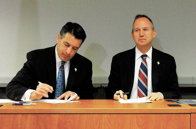 Nevada Gov. Brian Sandoval, left, and Delaware Gov. Jack Markell sign an agreement Tuesday morning in Wilmington, Del., that joins the states in a partnership for online poker. (Steve Tetreault/St ...