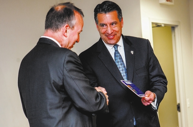Nevada Gov. Brian Sandoval  presents a Nevada License plate to Delaware Governor Markell during a news conference on Tuesday, Feb. 25, 2014 in Wilmington, Del.  Poker players in Delaware and Nevad ...