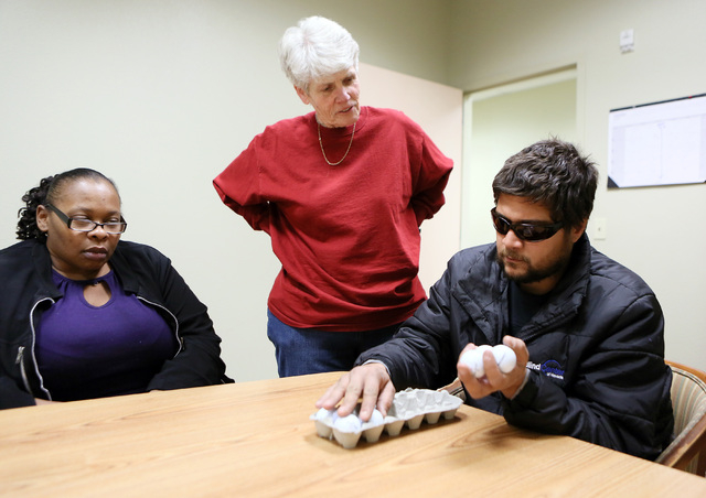 From left, student Erin Patrick and instructor Jean Peyton listen and watch as student Tony Behn practices the alphabet in Braille by using golf balls and an egg carton during Blindconnect’s Tra ...