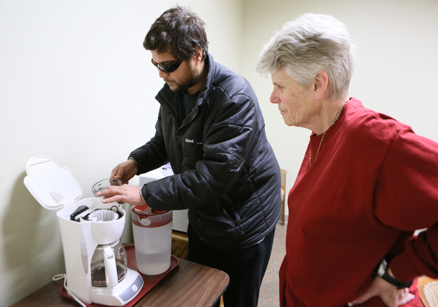 Student Tony Behn, left, pours water into a coffeemaker by feeling the edge of the water reservior as Jean Peyton stands nearby during Blindconnect’s Transition2 class at CSN, Feb. 7. (Ronda Chu ...