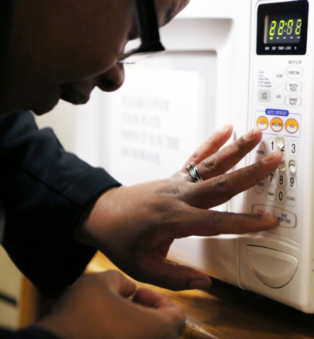 Student Erin Patrick feels the buttons on a microwave in order to know where to place another Bump-Dot that will assist with knowing which buttons go with which numbers during Blindconnect’s Tra ...