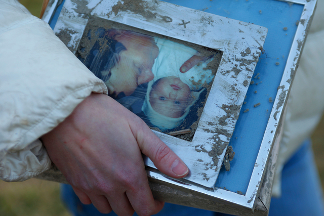A woman holds family photos pulled from the rubble at the site of Saturday's fatal mudslide near Oso, Wash., Sunday, March 23, 2014. (AP Photo /The Herald, Genna Martin)