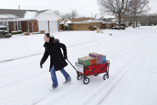 Girl Scout Katie Francis pulls her wagon full of boxes of cookies in the snow through a neighborhood in Warr Acres selling cookies in Oklahoma City. (AP Photo/The Oklahoman, Doug Hoke, File)