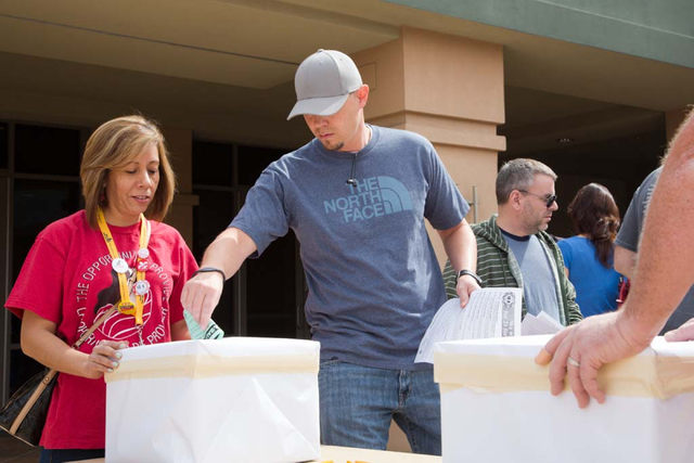 Culinary Union member and Margaritaville employee, Jeff Baadsgaard, casts his ballot as 12 year union member, Martha Mendez, looks on at the East Las Vegas Community Center on Thursday, March 27,  ...