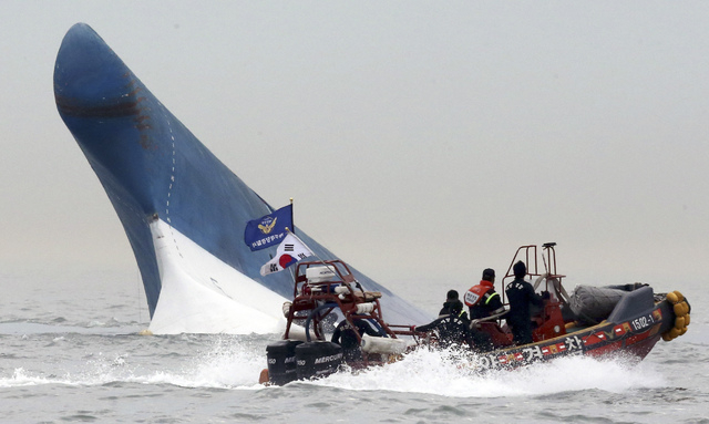 South Korean coast guard officers try to rescue passengers from a ferry sinking in the water off the southern coast near Jindo, south of Seoul, South Korea, Wednesday, April 16, 2014. The ferry ca ...