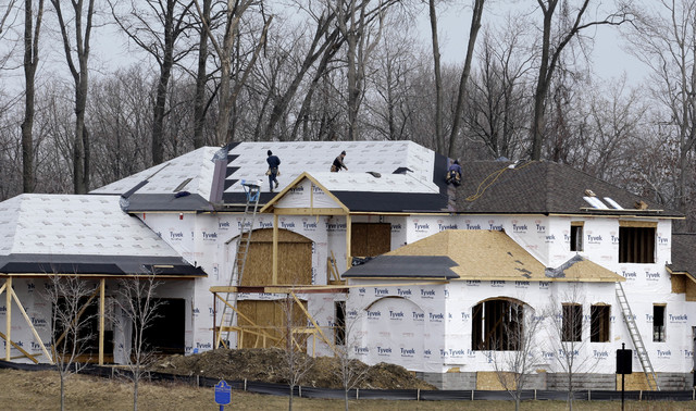 This Friday, March 21, 2014 photo shows roofers installing a roof on a new construction home in Pepper Pike, Ohio. The Commerce Department reports on U.S. home construction in March later Wednesda ...