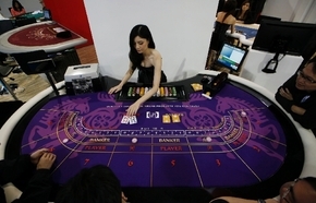 An attendant demonstrates the game of baccarat on a baccarat gaming table during the Global Gaming Expo Asia in Macau on May 23. Almost all of Macau's $38 billion in gambling revenue last year - ...