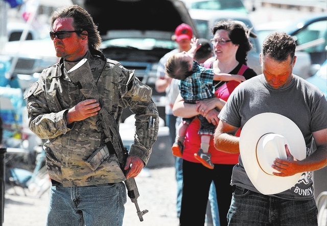 An armed man attends a ceremony near Cliven Bundy's ranch in Bunkerville on Sunday, April 13, 2014. Bundy and the Bureau of Land Management  reached a deal to stop the cattle roundup on Saturday.  ...