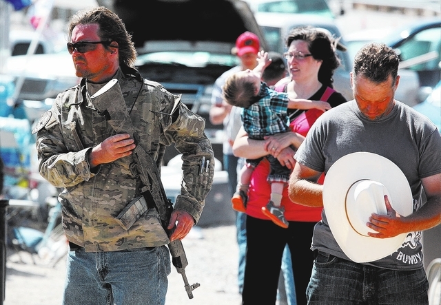 An armed man attends a ceremony near Cliven Bundy's ranch in Bunkerville on Sunday, April 13, 2014. Bundy and the Bureau of Land Management reached a deal to stop the cattle roundup on Saturday. ...