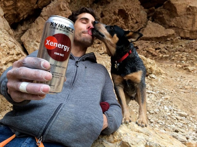 Joe Kinder takes a break from rock climbing in an area called Cathedral in Southern Utah to get a kiss from his dog, Finn, in this undated photo. He holds a drink from his new sponsor, Xyience, a  ...