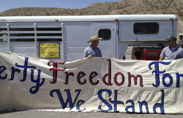 Kolby Hughes, right, and John Banks, left, and Kolby Hughes help hold up a sign in support of rancher Cliven Bundy near Bunkerville, Nev. Monday, April 7, 2014. (John Locher/Las Vegas Review-Journal)