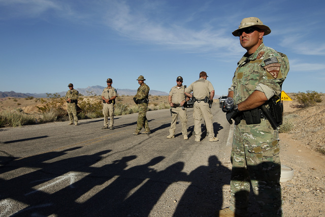 Federal law enforcement officers block a road at the Lake Mead National Recreation Area near Overton, Nev. Thursday, April 10, 2014. In the foreground are the shadows of protestors. Two people wer ...
