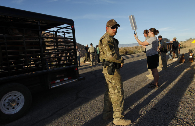 Federal law enforcement officers guard a convoy of cattle at the Lake Mead National Recreation Area near Overton, Nev. Thursday, April 10, 2014. Two people were detained while protesting the round ...