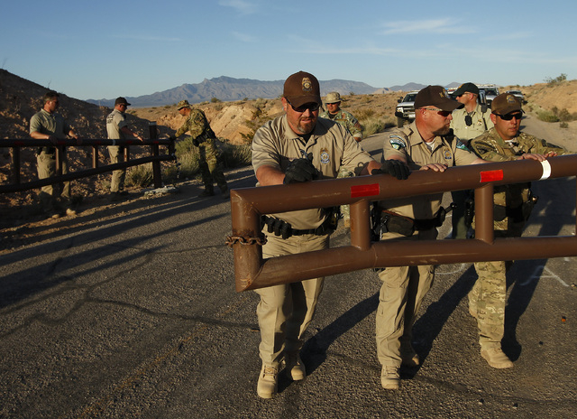 Federal law enforcement officers open a gate to allow a convoy of cattle to get through at the Lake Mead National Recreation Area near Overton, Nev. Thursday, April 10, 2014. Two people were detai ...