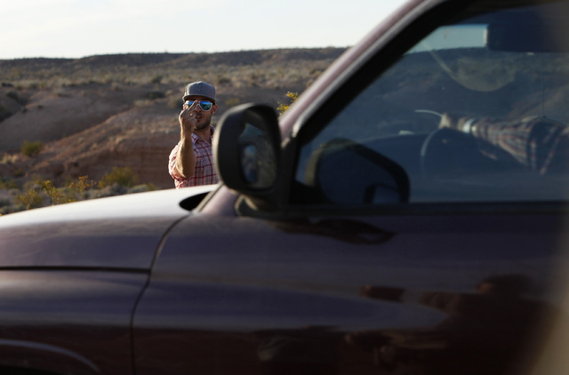 A protestor motions towards a convoy of cattle at the Lake Mead National Recreation Area near Overton, Nev. Thursday, April 10, 2014. Two people were detained while protesting the roundup of cattl ...