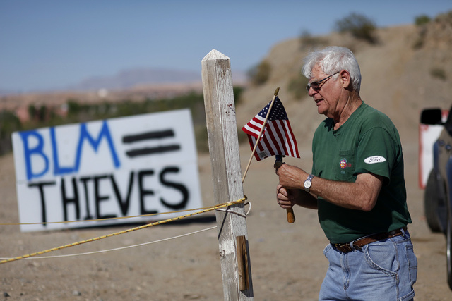 Jim Olson puts up a flag near what was the Bureau of Land Management's "first amendment area" in Bunkerville, Nev. Thursday, April 10, 2014. The Bureau of Land Management removed their t ...