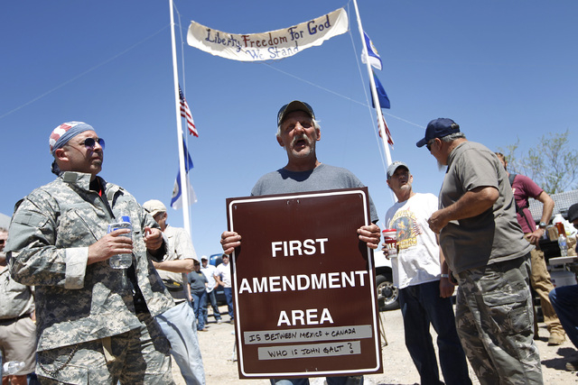 Charlie Brown holds up a sign from the Bureau of Land Management's "first amendment area" during a protest of the Bureau of Land Management's roundup of cattle near Bunkerville, Nev. Thu ...
