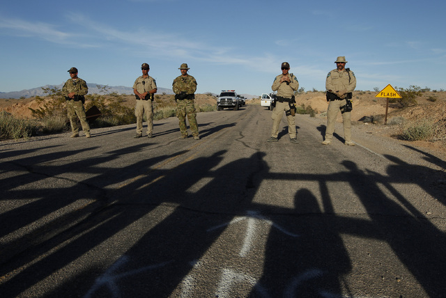 Federal law enforcement officers block a road at the Lake Mead National Recreation Area near Overton, Nev. Thursday, April 10, 2014. In the foreground are the shadows of protestors. Two people wer ...