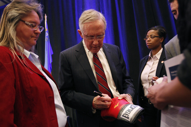 U.S. Sen. Harry Reid, D-Nev., signs a boxing glove after the Las Vegas Review-Journal's Hashtags & Headlines event at Paris Hotel & Casino in Las Vegas on Thursday. (John Locher/Las Vegas Review-J ...