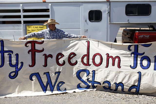 John Banks holds up a banner during a rally in support of Cliven Bundy near Bunkerville Nev. Monday, April 7, 2014, 2014. The Bureau of Land Management has begun to round up what they call "t ...