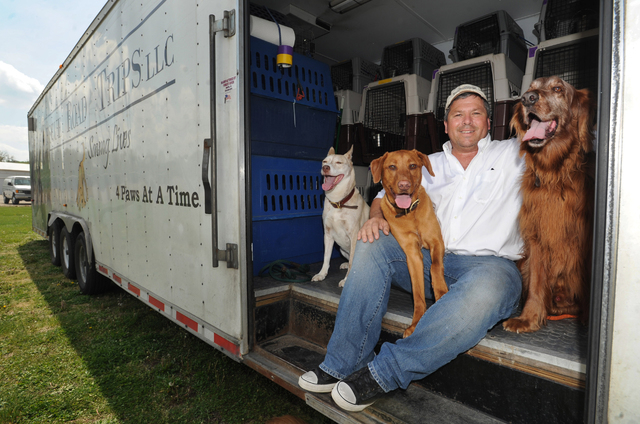 In this May 8, 2014 photo, Greg Mahle poses with his dogs Murphy, Beans and Treasure, in the Rescue Road Trips trailer. Mahle drives more than 40,000 miles a year rescuing dogs from shelters and p ...