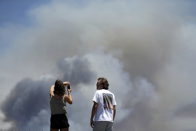 Chase and Brittany Boslet take pictures of smoke from the Las Pulgas fire burning on the Marine Corps Camp Pendleton base Friday, May 16, 2014, from a highway rest area near  Oceanside, Calif. San ...