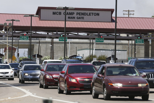Cars leave the Marine Corps Camp Pendleton base during a partial evacuation due to wildfires Friday, May 16, 2014, in Oceanside, Calif. San Diego County officials said Friday five wildfires have b ...