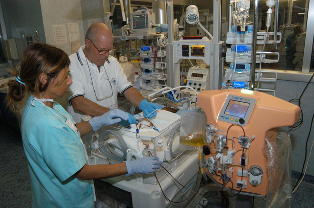 In this image made available by the San Bortolo Hospital in Vicenza on Thursday May 22, 2014 a nurse Mariangela Mettifogo, left, and Dr. Claudio Ronco treat a baby hooked up to a new dialysis mach ...