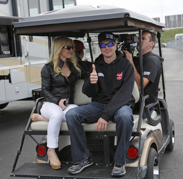 In this May 17, 2014 file photo, Kurt Busch, right, gives a thumbs-up as he rides on a golf cart with his girlfriend, Patricia Driscoll, to prepare for the NASCAR Sprint All-Star auto race at Char ...