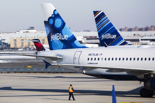 An airport worker leads JetBlue planes onto the tarmac of the John F. Kennedy International Airport in New York December 11, 2013. (REUTERS/Lucas Jackson)
