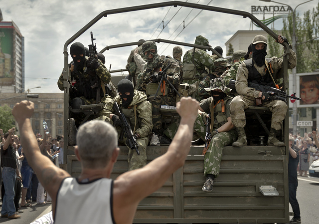 A man cheers as pro-Russian gunmen drive away in a truck in Lenin square in Donetsk, Ukraine, Sunday, May 25, 2014. A convoy of an armored personnel carrier and seven trucks carrying several hundr ...