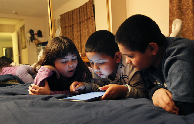 From left, friends Annakaren Villalobos, Anthony Ruiz, and Omar Calderon play a video game together in Ruiz's parent's room at his home in Las Vegas on Thursday, Feb. 27, 2014. All three children  ...