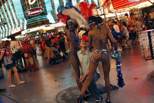 Auriel Serai, left, and partner Adri Moore, otherwise known as "The American Beauties," pose for a paid portrait with a visitor to the Fremont Street Experience in Las Vegas on Thursday, ...