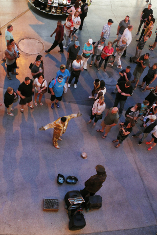 Goldmine, middle in gold suit, requests tips from people who gathered to see him perform at the Fremont Street Experience in Las Vegas on Thursday, May 22, 2014. (Jason Bean/Las Vegas Review-Journal)