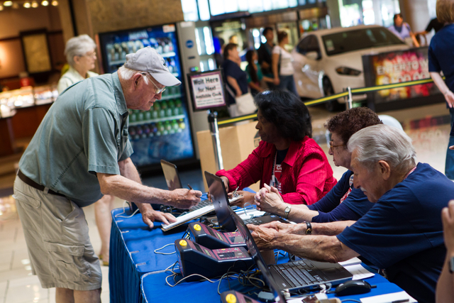 James Green of Las Vegas , left, signs in to cast his ballot on the first day of early voting at the Meadows Mall in Las Vegas on Saturday, May 24, 2014. (Chase Stevens/Las Vegas Review-Journal)