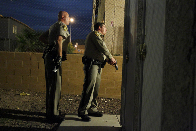 Las Vegas police officer Paul Hunter, left, and and unidentified officer check an apartment building, guns in hand, where shots were reported fired in Las Vegas Friday, Oct. 14, 2011. (John Locher ...