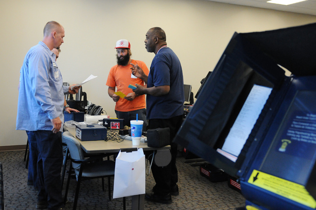 Program assistant instructor Matthew Goins, from right, trains volunteers David Vargas and Cody Cunningham about how to assist voters during a poll worker training class at the Clark County Electi ...
